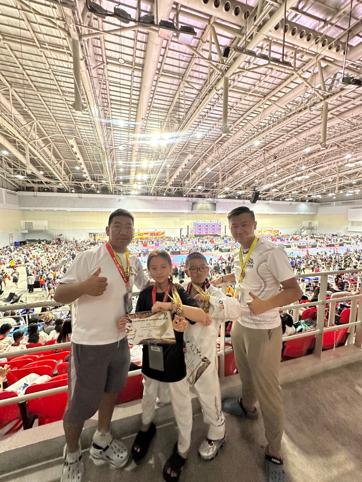 两名青少年运动员佩戴奖牌与教练合影